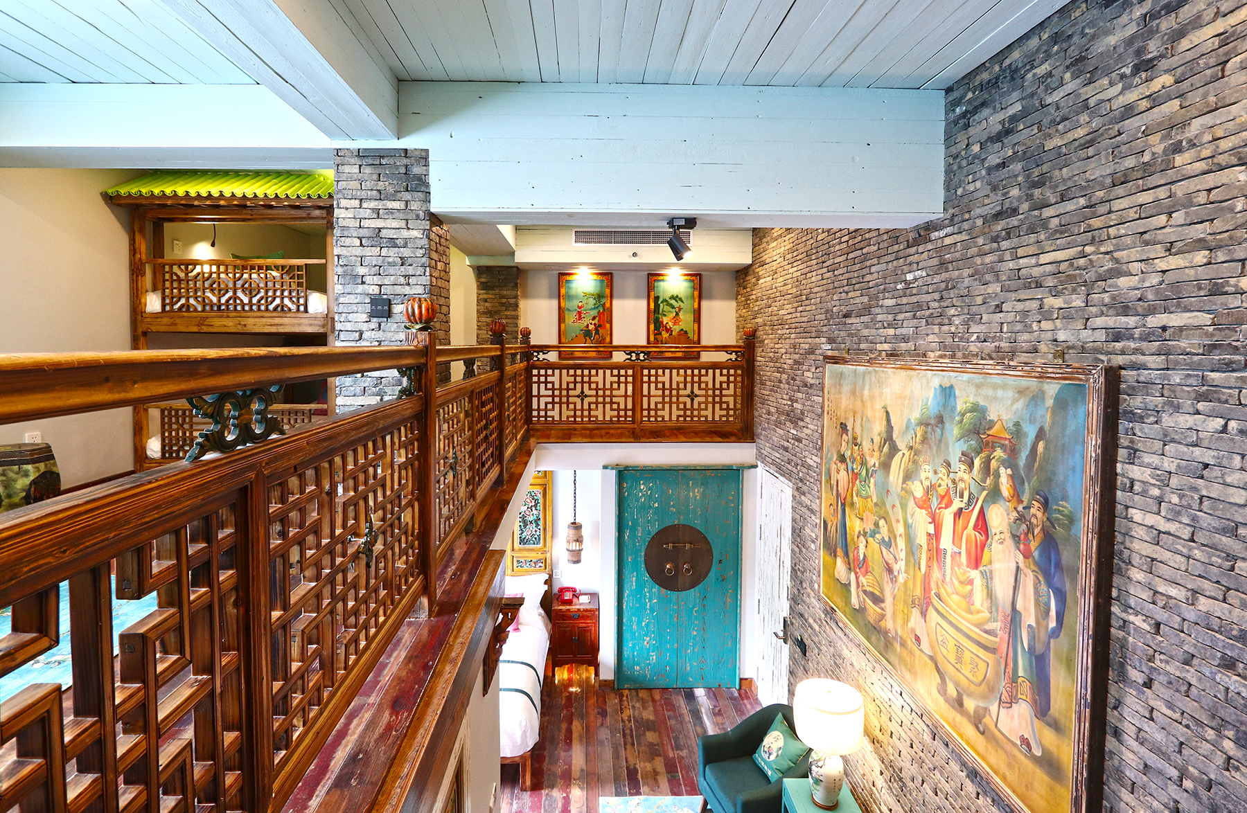 A duplex loft room at Six Arts Museum Hotel with carved timber balustrades, grey brick walls and a painted heritage mural